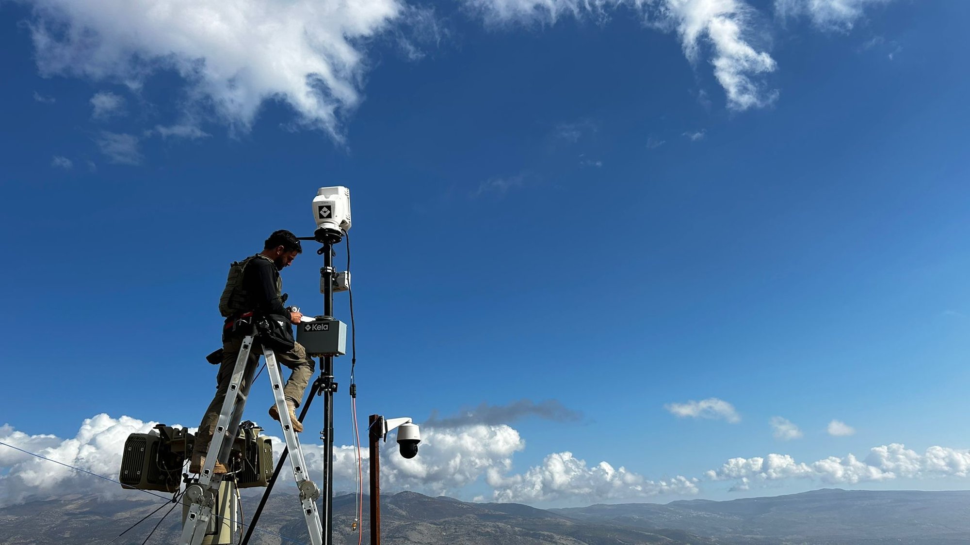 A Kela operator installs a multi-sensor stack on a mast in the field